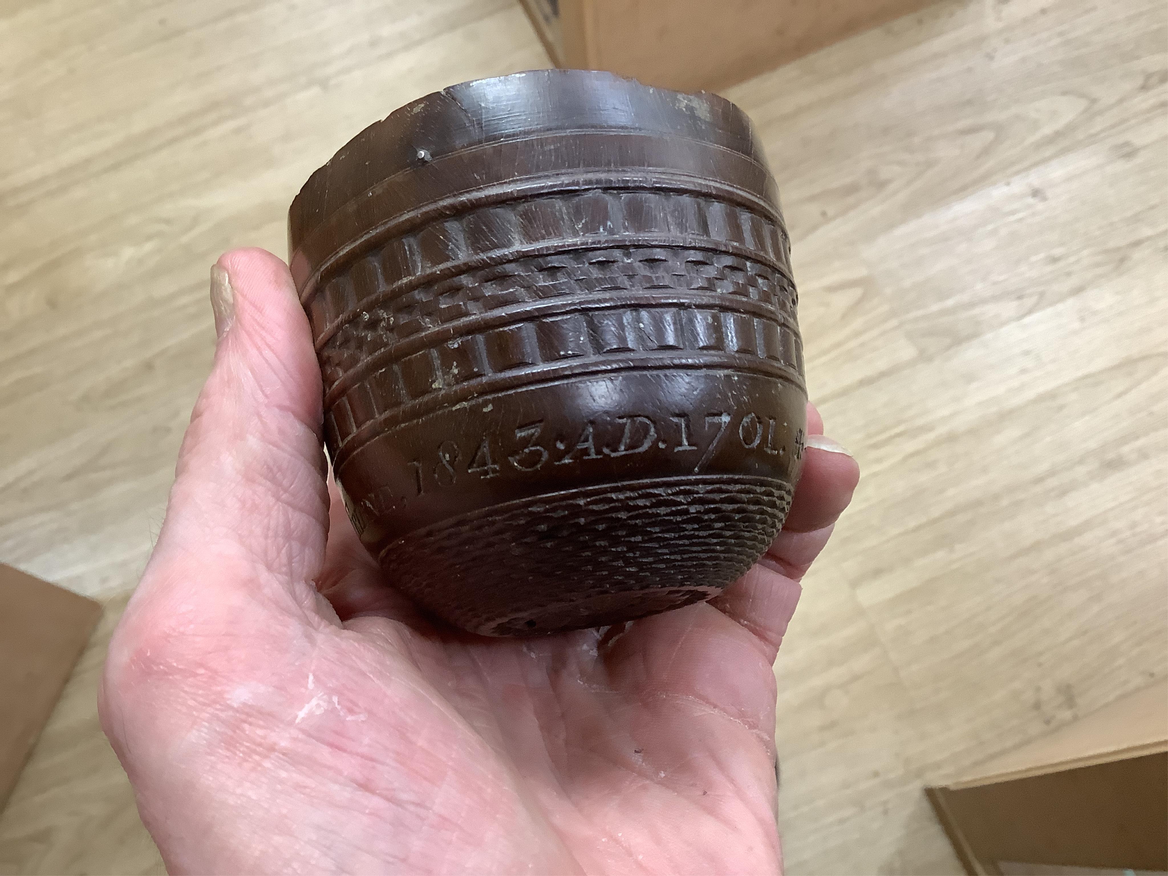 A 19th century or earlier engine-turned lignum vitae tumbler cup, engraved ‘Presented to M. S. Jones by a Friend 1843 AD 1701 +’, 6.5cm high, by repute found on the roof plate of Kenwood house London in 2012, during reno